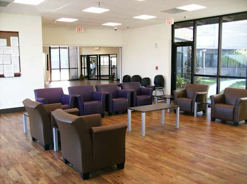 A waiting room with purple and brown chairs and a white wall.